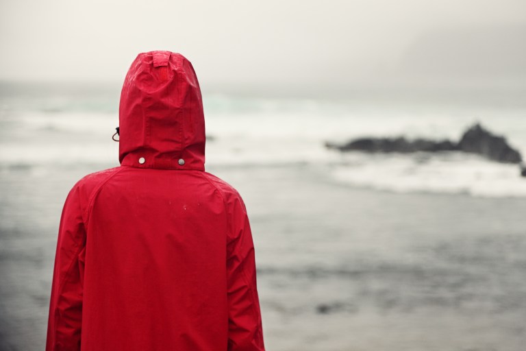 Fall woman in rain looking at ocean